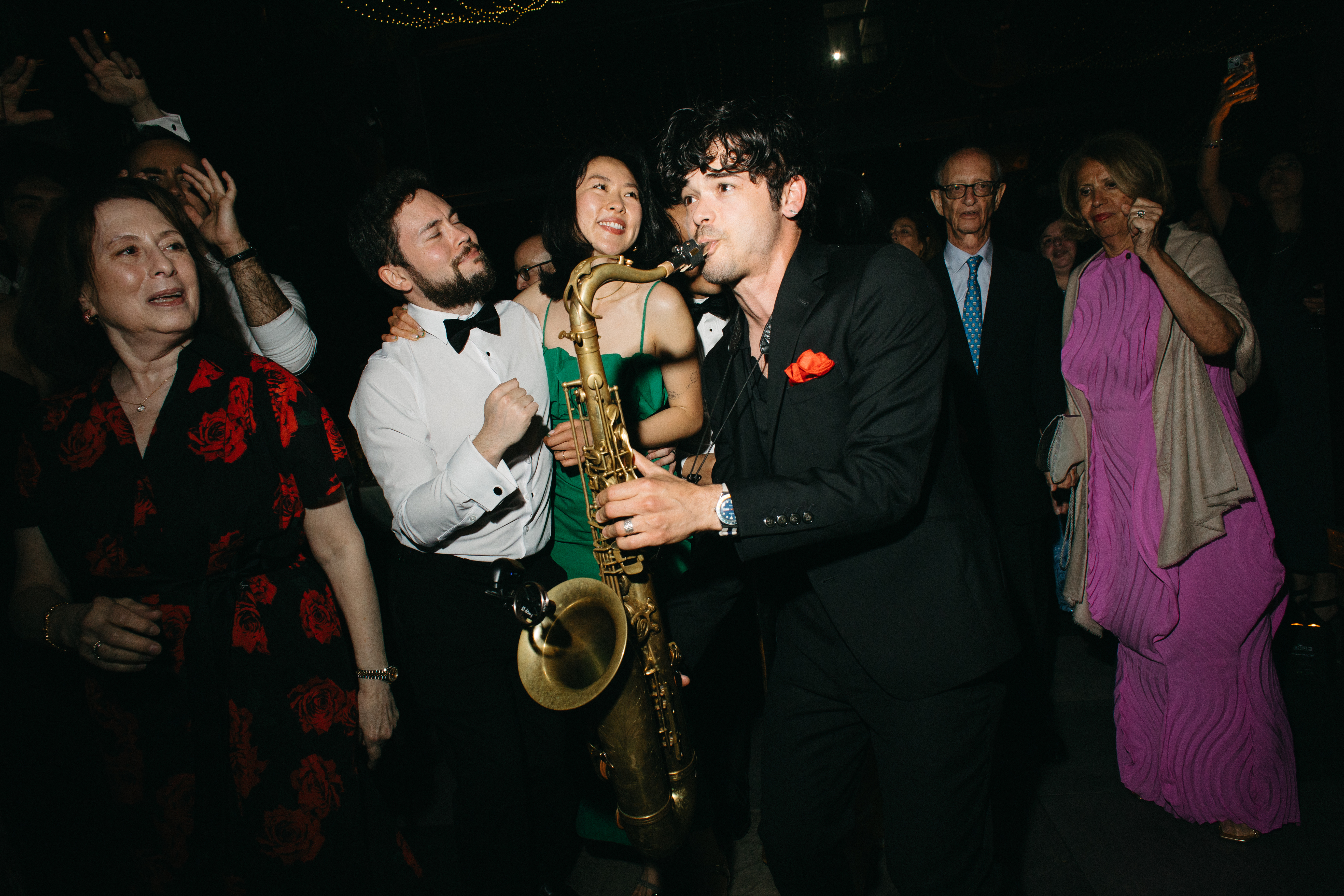Steve Mode playing saxophone among wedding guests of all ages